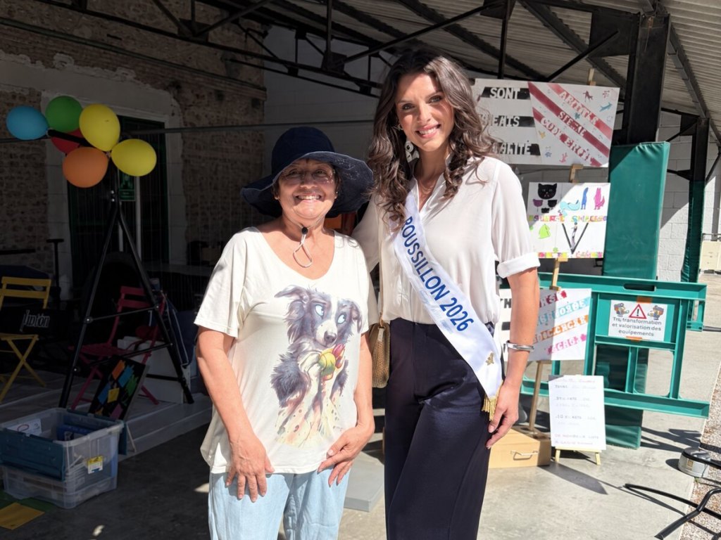 Une bénévole d’ASCaMaC aux côtés de Miss Roussillon 2026 devant le stand de sensibilisation.