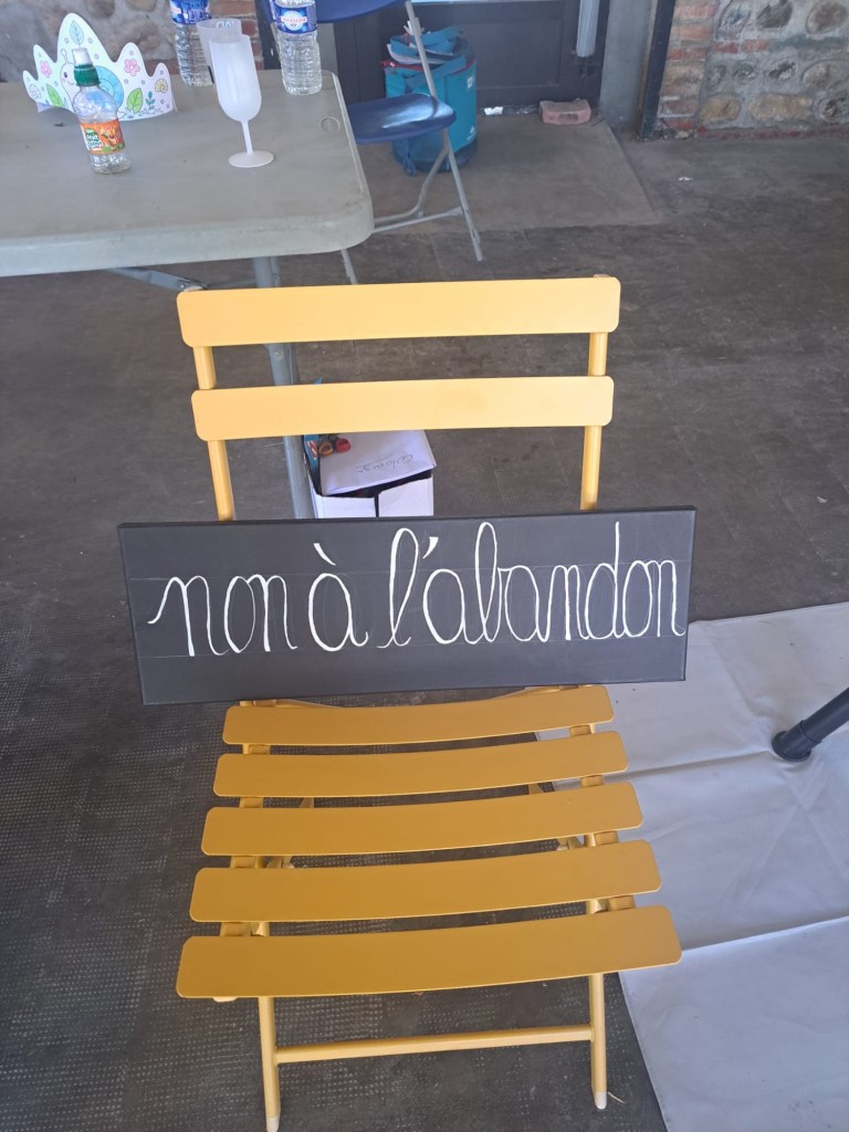 Chaise jaune portant un panneau noir manuscrit « non à l’abandon ».