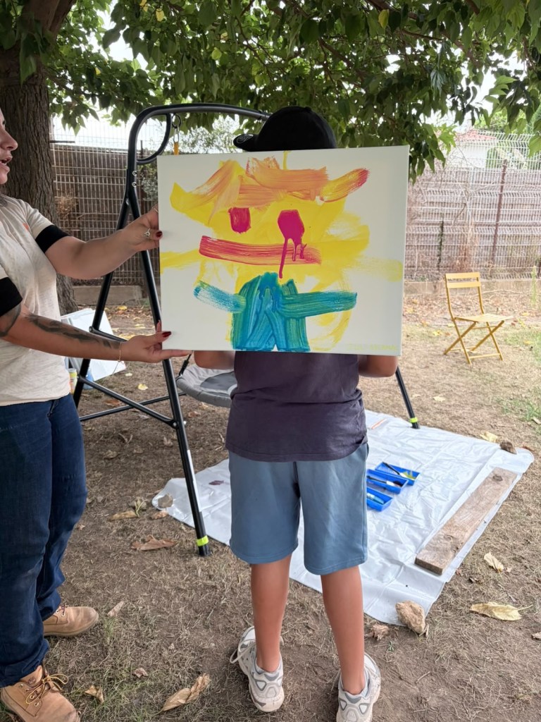Un enfant vu de dos présente une peinture colorée réalisée pendant les activités.